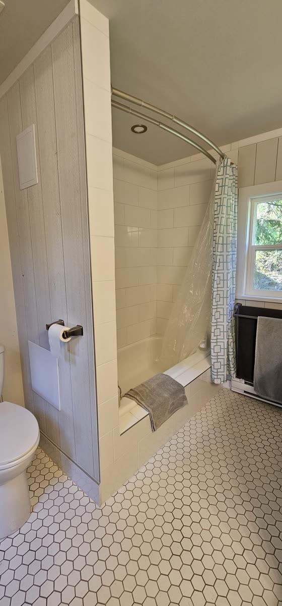 Bathroom renovation — subway tile tub surround, curved rod, hex tile floor
