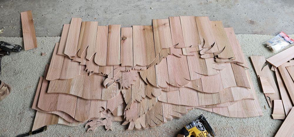 Custom cedar raven carving in-progress — raw cedar planks laid out before staining