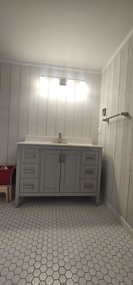 Completed bathroom — grey shiplap, hex tile floor, vanity with quartz top